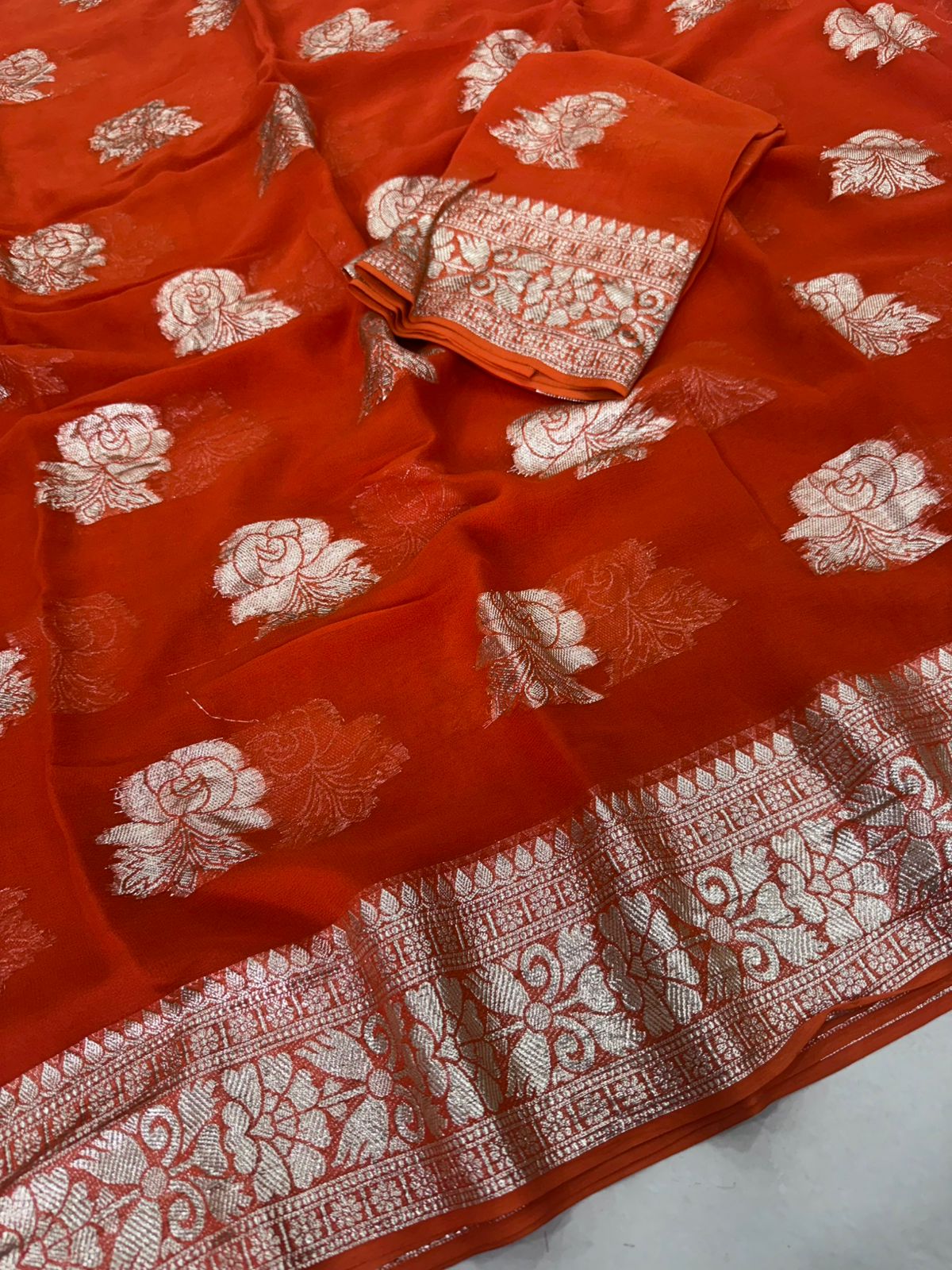 Viscose Georgette Saree with Contrast Blouse in Rust Orange Gold shade featuring floral zari motifs and elegant woven border.