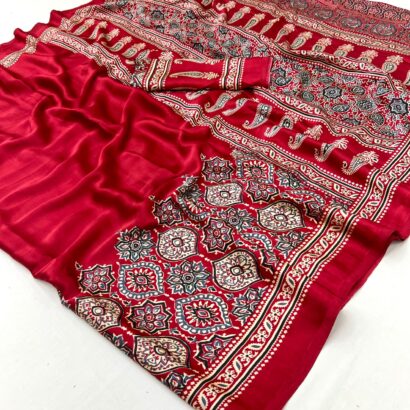 Red Ajrakh Satin Silk Saree in premium Modal Satin Silk with elegant digital print, tassels on pallu, 6.3 meter saree with matching blouse piece for festive and party wear.