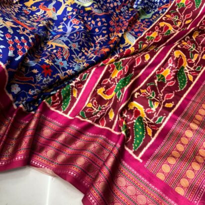 Blue Patola Silk Saree with Shikargah Print featuring intricate deer, elephant and bird motifs, rich sapphire blue double ikat design, magenta border, and gold zari pallu for festive and wedding wear.